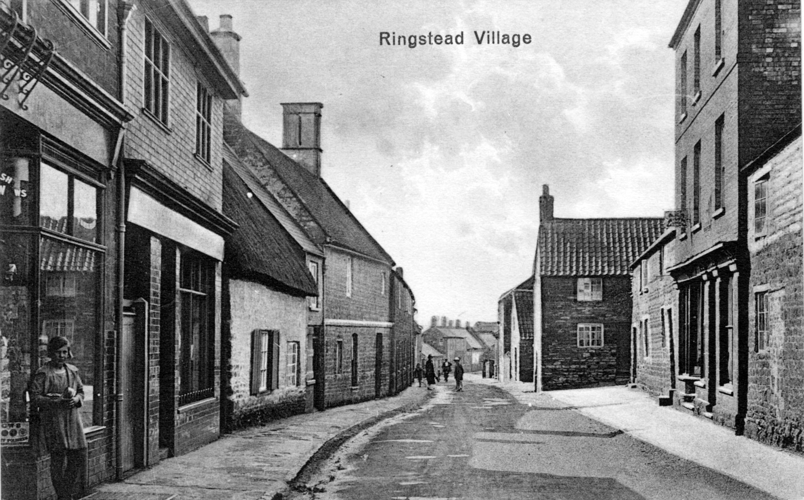 Ringstead High Street in 1920s. Girl is leaning against Co-op window (Londis 2013) 1920s postcard. Author's own copy