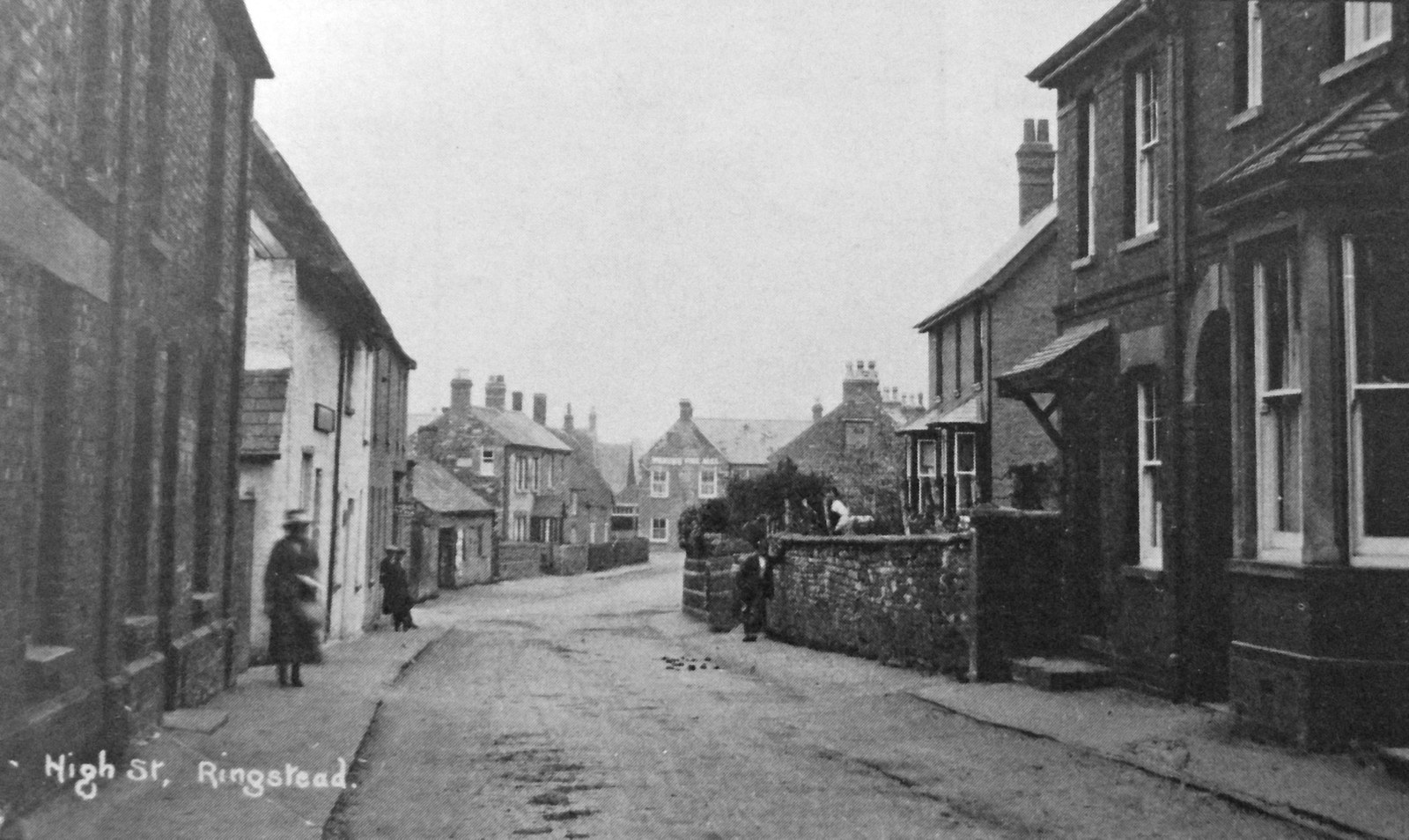 A 1920s view of the Old Bakehouse from the opposite direction showing the Swan in the distance [The Bakery is the white building on the left. You can just see the shop sign over the door. The first building on the left had been the Post Office at the end of the Nineteenth Century]
