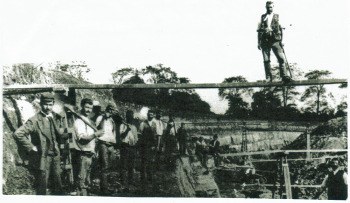 About 1910. This picture shows a large gang of men working in one of the quarries removing the overburden. There are a lot of trestles and planks bridging the quarry to provide access to the dump side where the overburden spoil was tipped from the barrows.