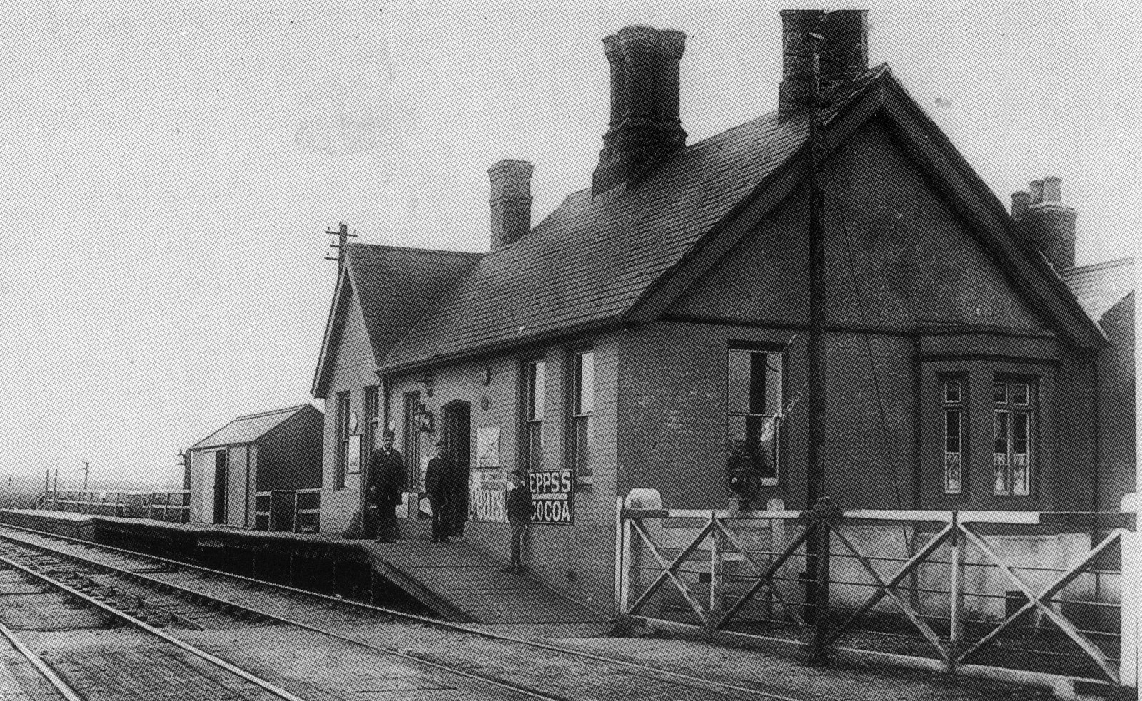 A later postcard of Ringstead & Addington Station (Frederick George is now the stationmaster). It looks as if the station house extends at the back. When the second line was constructed a second platform was built on the other side of the crossing. By 1957 only the shack to the left of the building (or a similar replacement) remained. The original had probably been demolished after a fire. With the kind permission of the publishers.